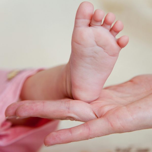 A tender close-up of a newborn's foot resting on a parent's hand, symbolizing care and love.